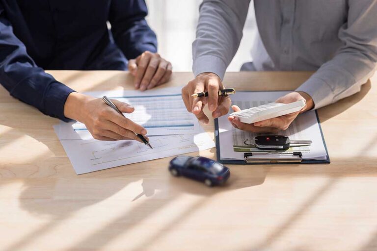 A homeowner reviews an insurance policy beside jewelry appraisal documents and household records.